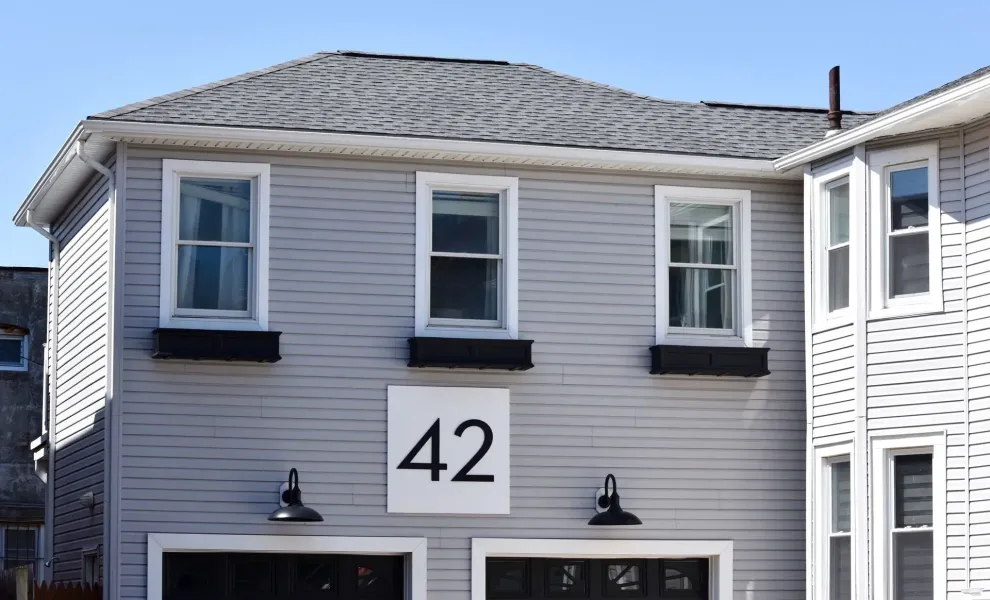 White seamless gutter along the eave of a gray-sided home numbered 42 in Atlantic City, NJ