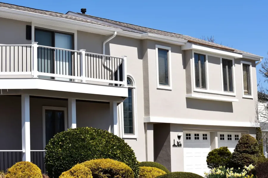 White seamless gutters and downspout on a tan stucco home with balcony in Brigantine, NJ