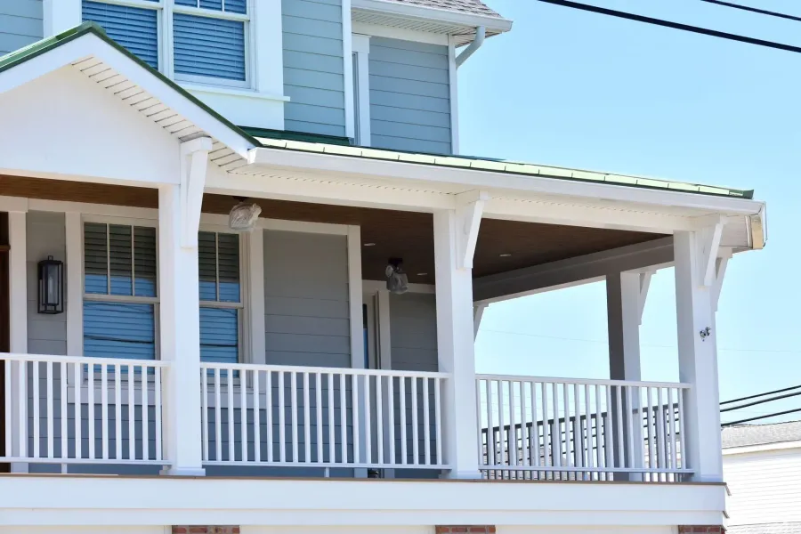 Blue clapboard home with white porch, green metal roof and seamless gutter in Longport, NJ