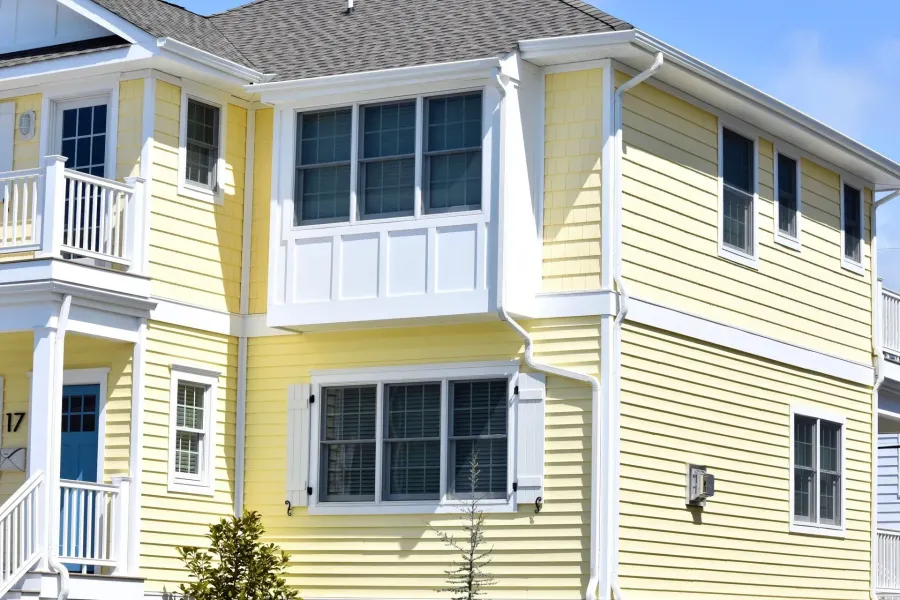 White seamless gutters and downspouts on a yellow two-story Margate, NJ coastal home