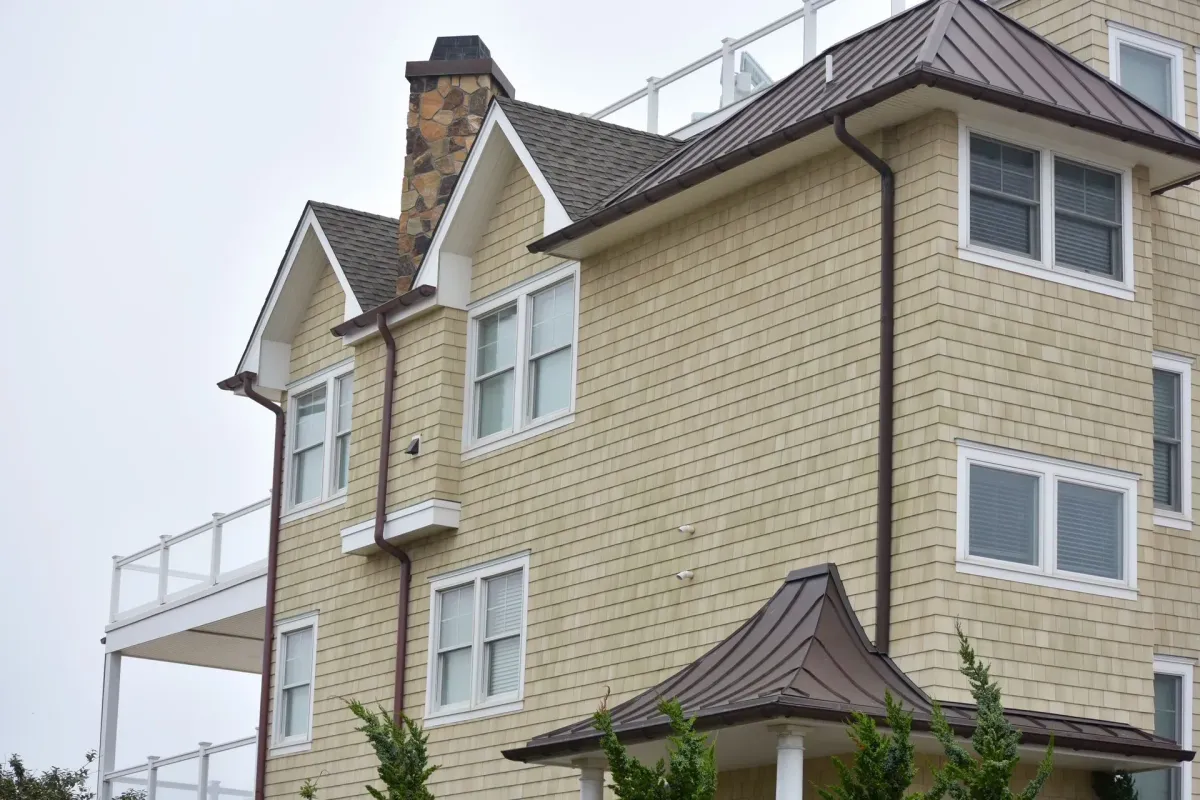 Bronze seamless gutter and downspout on a cedar-shingle home with metal roof in Sicklerville, NJ
