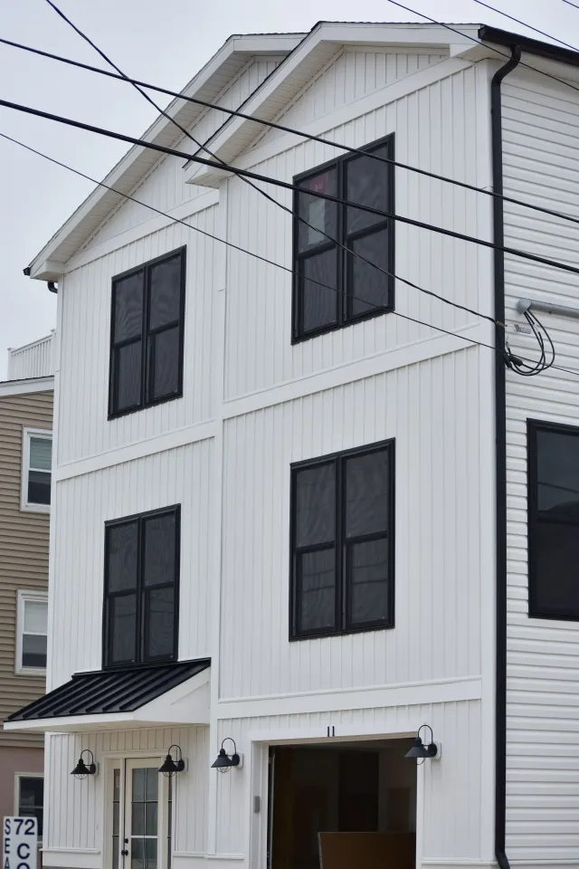Black downspout and white seamless gutters on a tall three-story home in Sicklerville, NJ