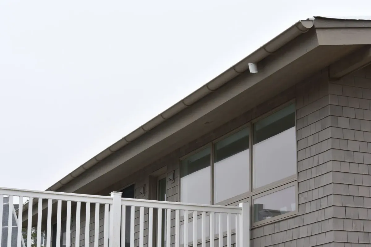 Tan half-round seamless gutter along a shingle-sided roof eave in Williamstown, NJ
