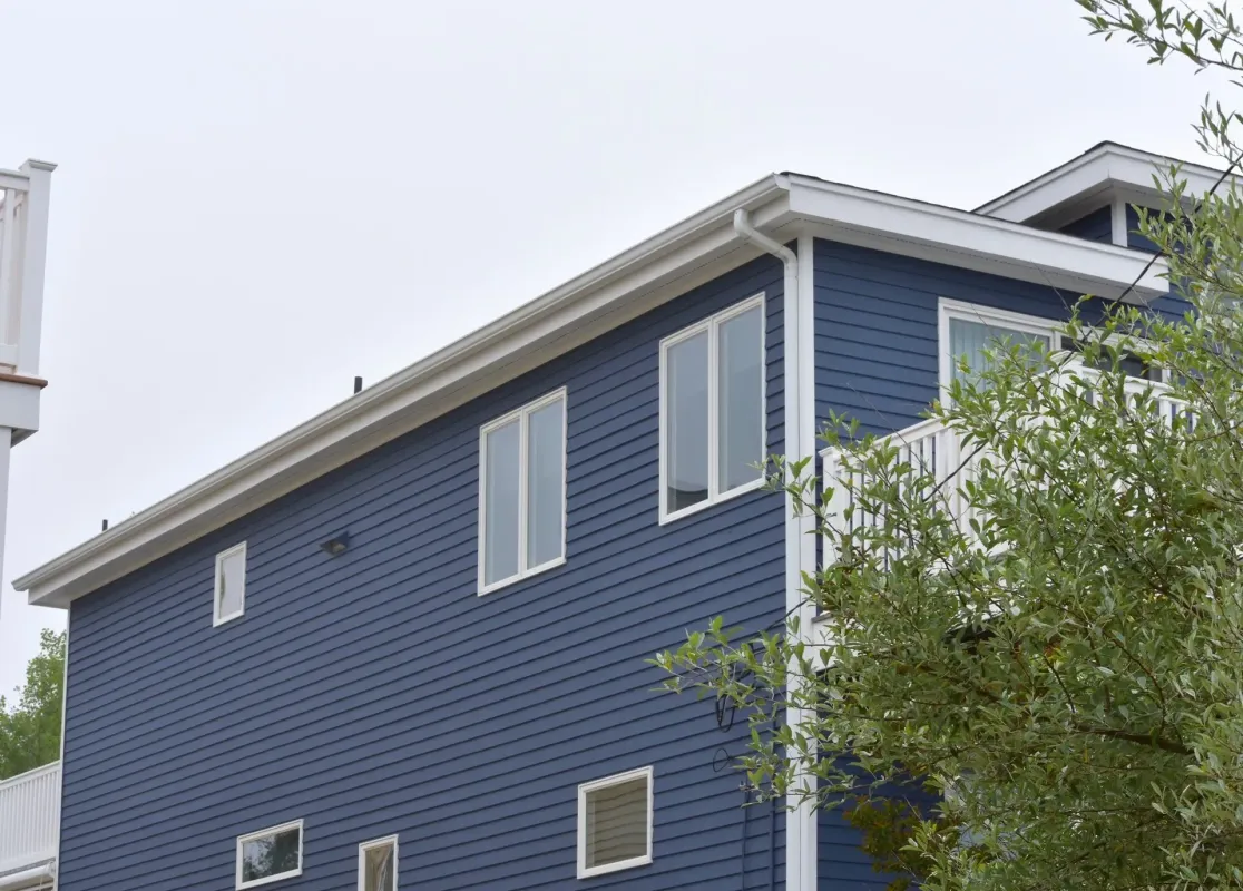 White seamless gutters wrapping the roofline of a navy blue clapboard home in Williamstown, NJ