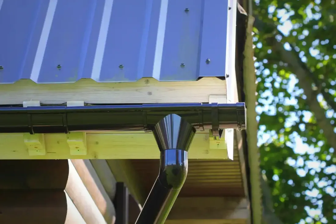 Downspout draining into a deck drain and river-rock bed